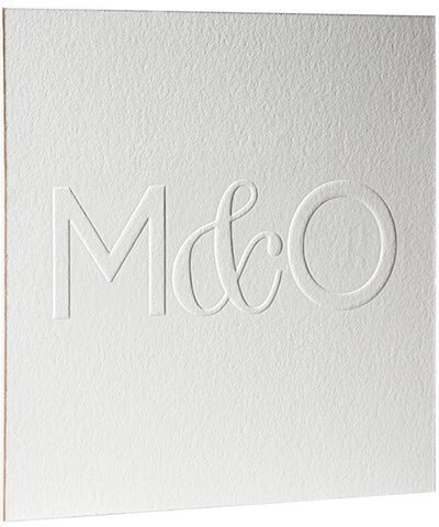 A white blind embossed card with the letters 