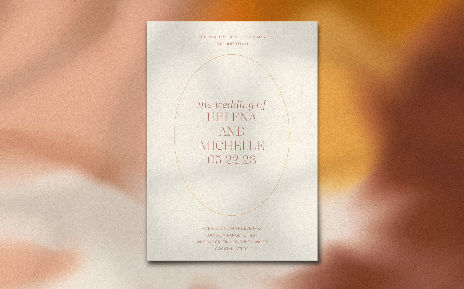 A cream colored wedding invitation with a tie-dye background featuring shades of orange and pink